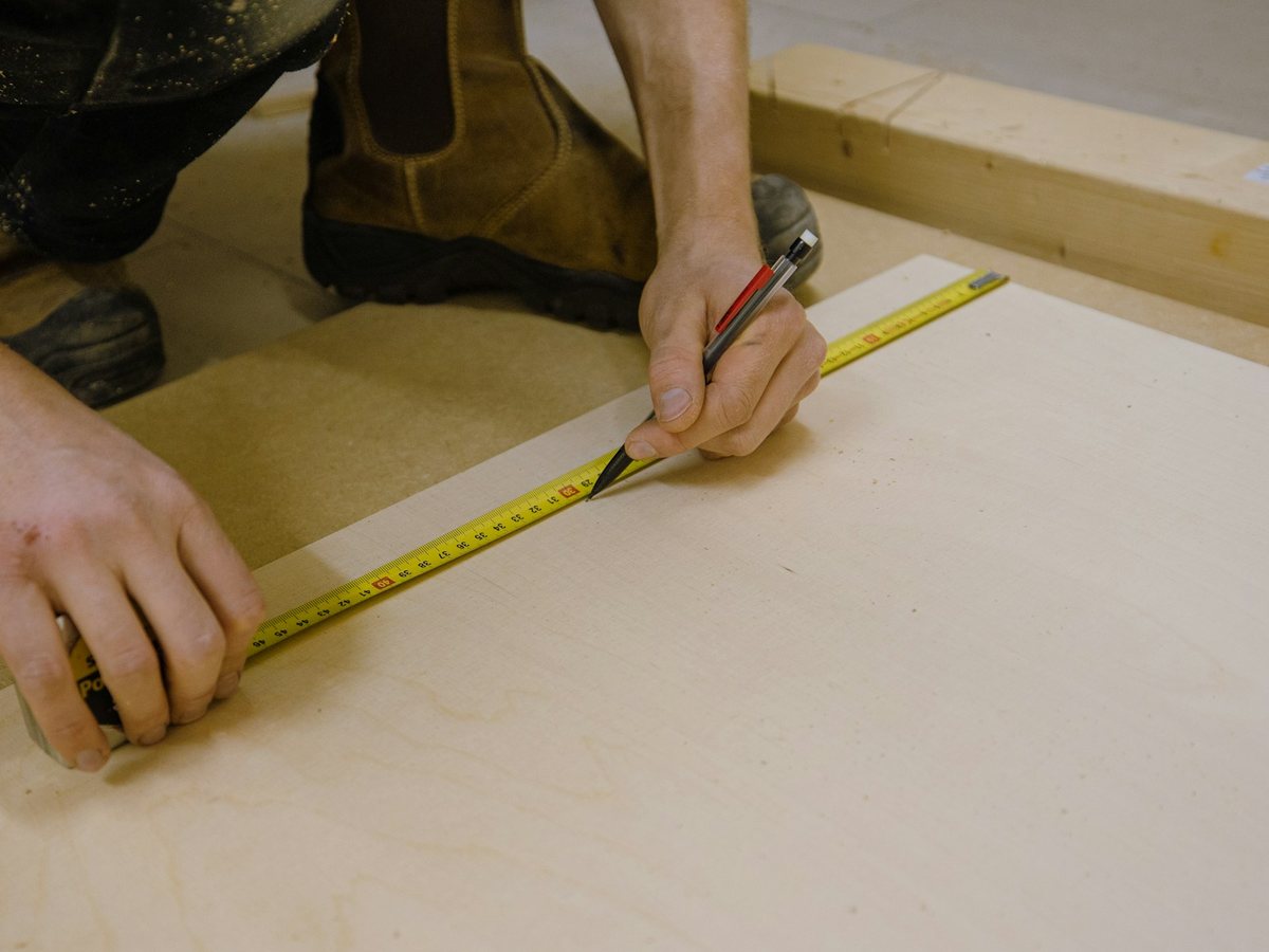 Artisan traçant un repère au crayon le long d'un mètre ruban
