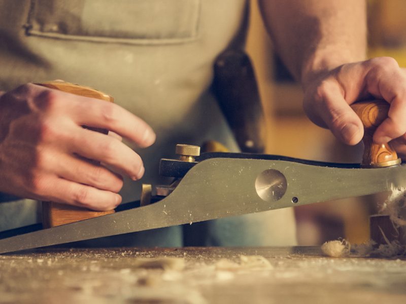 Menuisier travaillant une pièce de bois au rabot